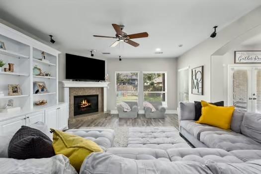 living room with ceiling fan, light hardwood / wood-style floors, built in shelves, and french doors