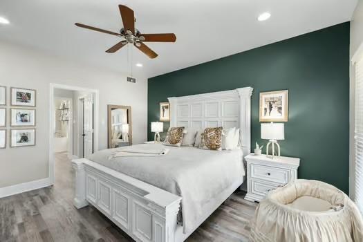 bedroom with ensuite bath, ceiling fan, and dark hardwood / wood-style flooring