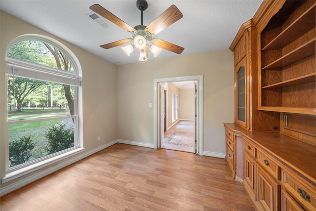 unfurnished dining area with ceiling fan and light wood-type flooring