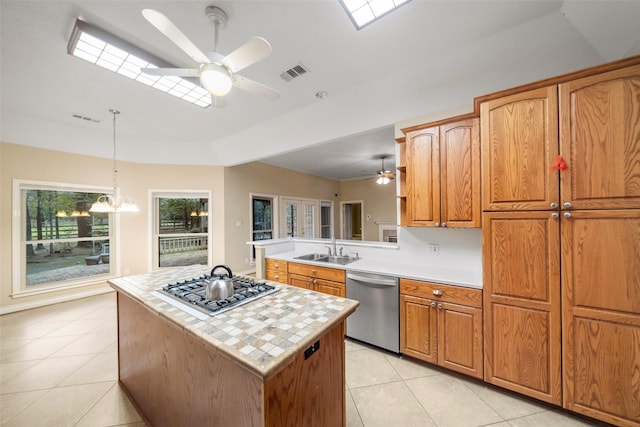 kitchen with pendant lighting, light tile patterned floors, a kitchen island, kitchen peninsula, and stainless steel appliances