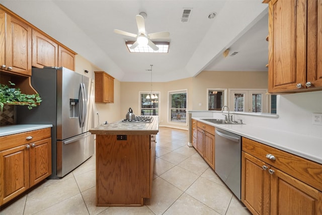 kitchen with appliances with stainless steel finishes, ceiling fan, sink, decorative light fixtures, and a kitchen island