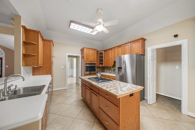 kitchen with backsplash, sink, ceiling fan, appliances with stainless steel finishes, and a kitchen island