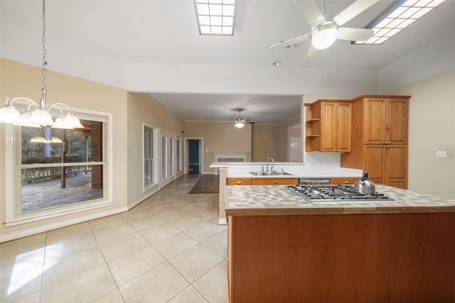 kitchen with kitchen peninsula, stainless steel appliances, sink, pendant lighting, and an inviting chandelier