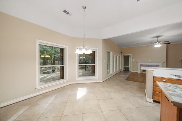 unfurnished dining area with light tile patterned floors and ceiling fan with notable chandelier