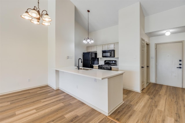 kitchen featuring pendant lighting, black appliances, a kitchen bar, kitchen peninsula, and a chandelier