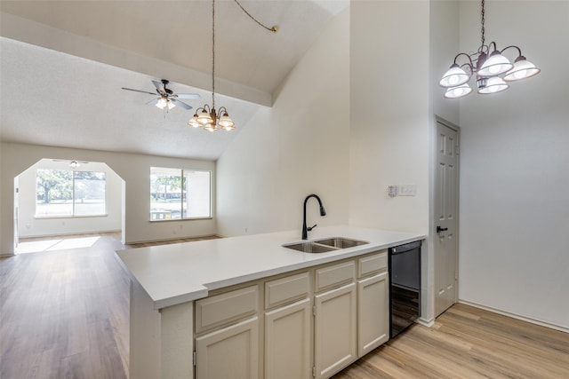 kitchen with kitchen peninsula, ceiling fan with notable chandelier, sink, light hardwood / wood-style flooring, and dishwasher