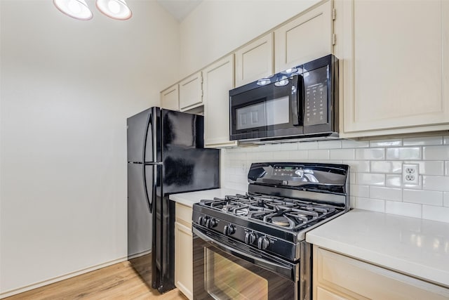 kitchen with tasteful backsplash, black appliances, and light wood-type flooring