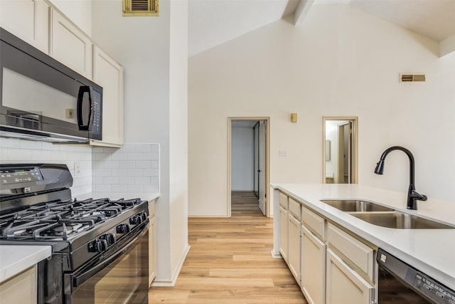 kitchen featuring high vaulted ceiling, black appliances, sink, light wood-type flooring, and beam ceiling