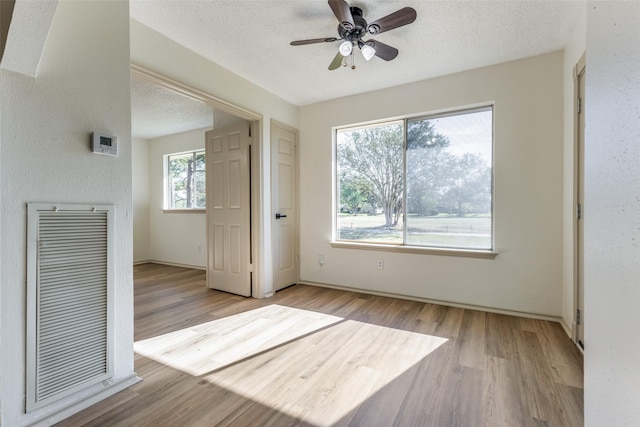 spare room with ceiling fan, light hardwood / wood-style floors, and a textured ceiling