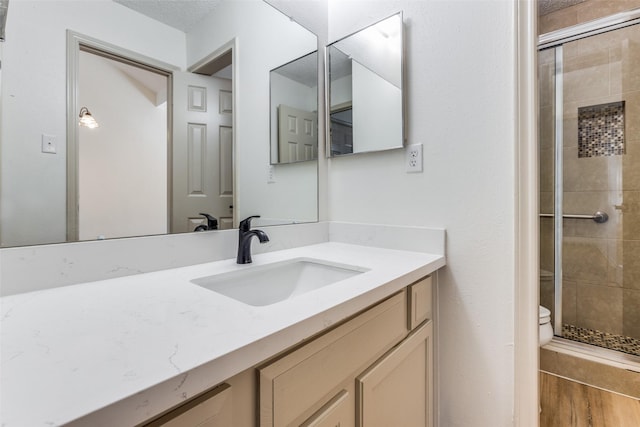 bathroom with vanity, hardwood / wood-style flooring, toilet, and walk in shower