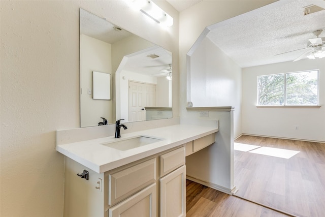 bathroom featuring vanity, wood-type flooring, a textured ceiling, and ceiling fan