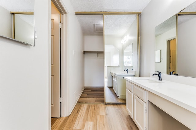 bathroom featuring wood-type flooring, vanity, and a textured ceiling