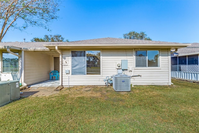 rear view of house featuring cooling unit and a lawn