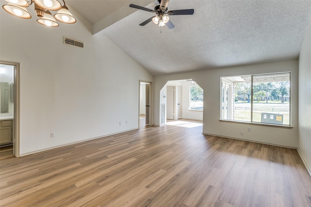 unfurnished living room with vaulted ceiling with beams, ceiling fan with notable chandelier, light hardwood / wood-style floors, and a textured ceiling