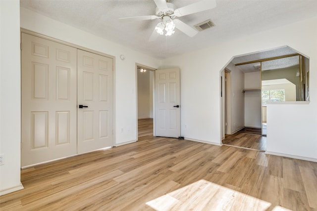 unfurnished bedroom with ceiling fan, light wood-type flooring, and a textured ceiling