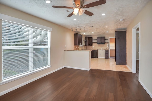 kitchen featuring decorative backsplash, rail lighting, a textured ceiling, ceiling fan, and light hardwood / wood-style flooring