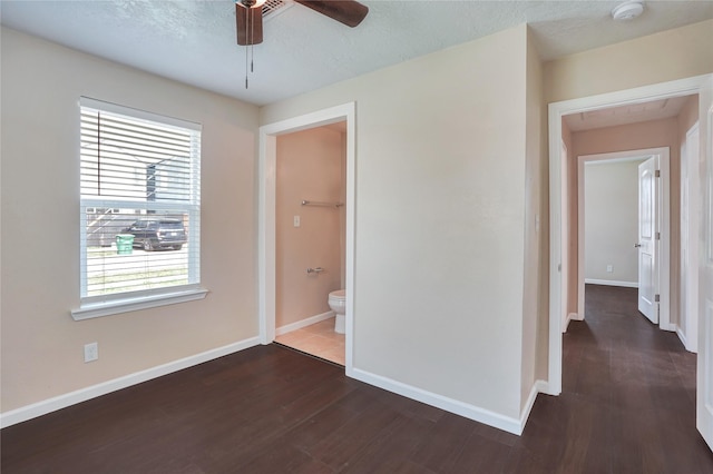 interior space with multiple windows, ceiling fan, ensuite bathroom, and dark wood-type flooring