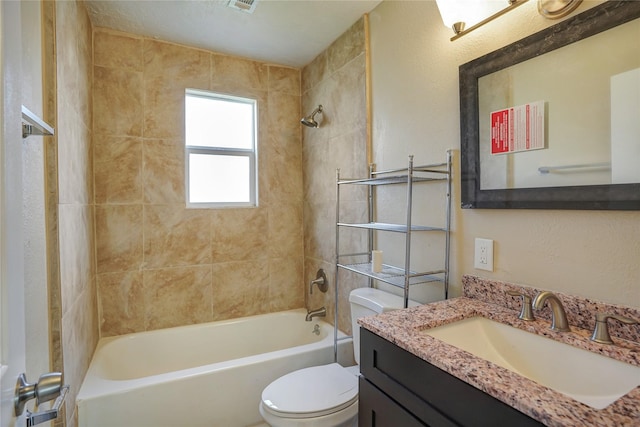 full bathroom featuring tiled shower / bath combo, toilet, and vanity