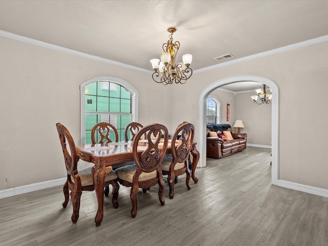 dining area featuring wood-type flooring, an inviting chandelier, and crown molding