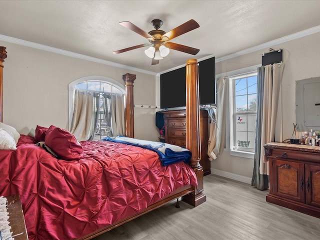 bedroom featuring ceiling fan, light hardwood / wood-style floors, ornamental molding, and electric panel