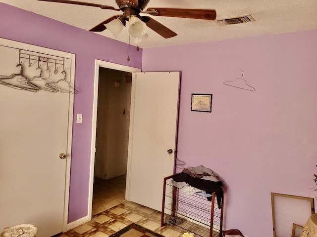 bedroom with ceiling fan and a textured ceiling