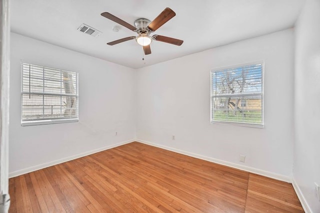 empty room with ceiling fan, a healthy amount of sunlight, and wood-type flooring