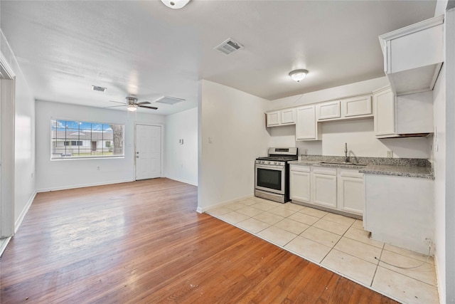 kitchen featuring gas stove, white cabinetry, sink, ceiling fan, and light wood-type flooring