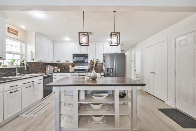 kitchen with white cabinetry, sink, hanging light fixtures, black appliances, and light wood-type flooring