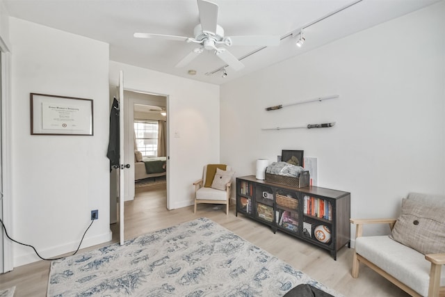 living area with light hardwood / wood-style floors, track lighting, and ceiling fan