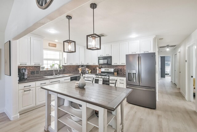 kitchen featuring black appliances, white cabinets, sink, hanging light fixtures, and light wood-type flooring