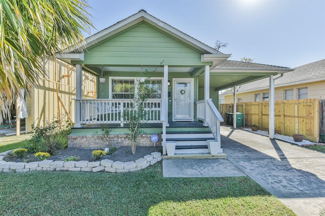 bungalow-style house featuring a carport, covered porch, and a front lawn