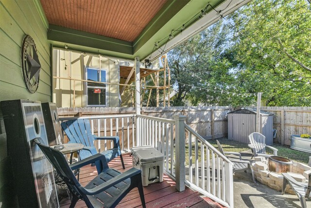 deck featuring grilling area, an outdoor fire pit, and a storage shed