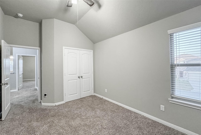 unfurnished bedroom with light carpet, a closet, ceiling fan, and lofted ceiling