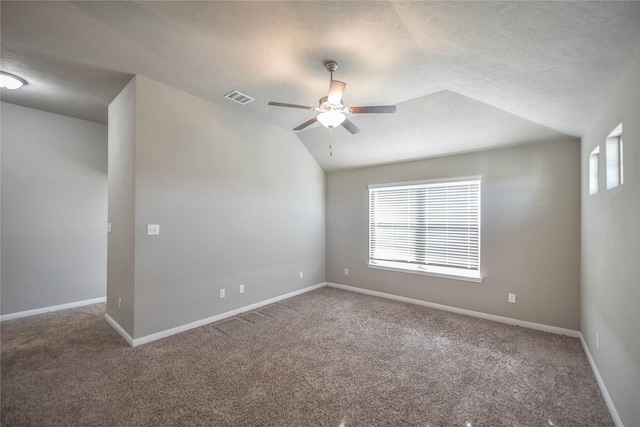 carpeted spare room with a textured ceiling, vaulted ceiling, and ceiling fan