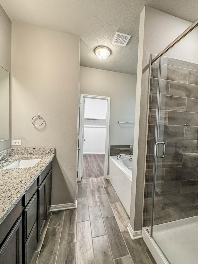 bathroom with vanity, a textured ceiling, and plus walk in shower