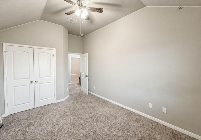 unfurnished bedroom with ceiling fan, a closet, carpet floors, and vaulted ceiling