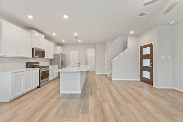 kitchen with sink, stainless steel appliances, an island with sink, decorative backsplash, and white cabinets