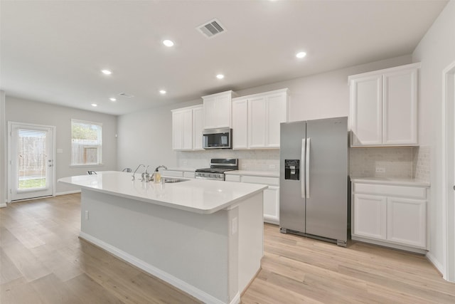 kitchen with a center island with sink, white cabinets, stainless steel appliances, and sink