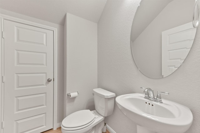 bathroom with toilet, sink, and vaulted ceiling