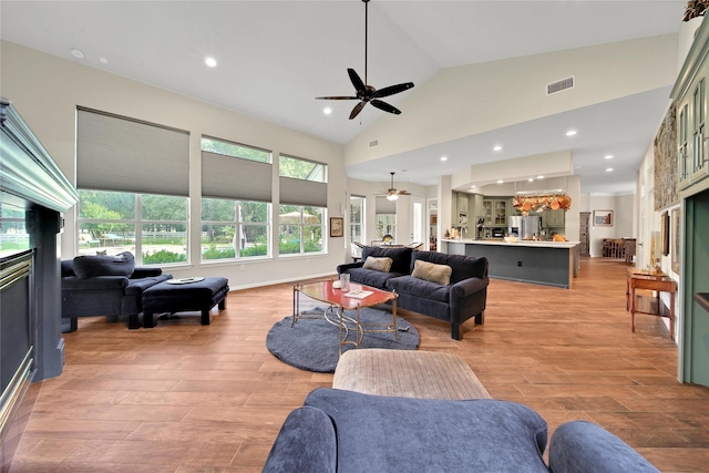 living room with ceiling fan, light hardwood / wood-style flooring, and high vaulted ceiling