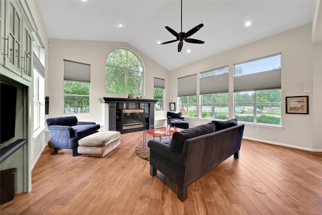 living room featuring light hardwood / wood-style floors, ceiling fan, a healthy amount of sunlight, and a tiled fireplace