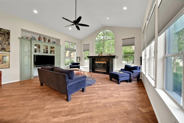 living room with ceiling fan, light hardwood / wood-style floors, and high vaulted ceiling