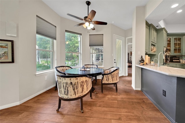 dining room with ceiling fan, sink, and wood-type flooring