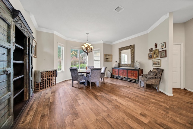 dining area featuring wood-type flooring, an inviting chandelier, and crown molding