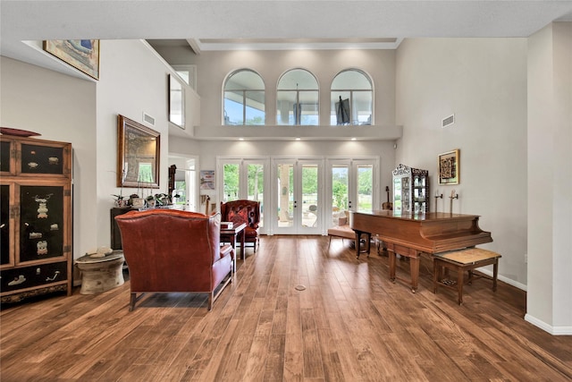 living room with hardwood / wood-style flooring, a high ceiling, and french doors