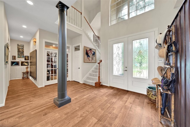 foyer entrance with a towering ceiling and light wood-type flooring