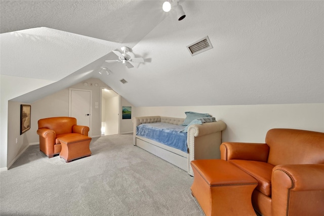 bedroom with ceiling fan, light colored carpet, lofted ceiling, and a textured ceiling