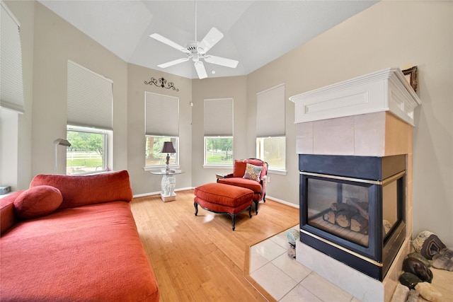 living room featuring a tile fireplace, ceiling fan, and wood-type flooring