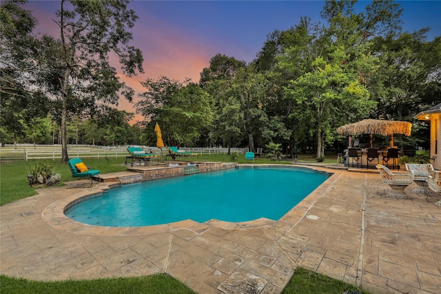 pool at dusk featuring a yard and a patio