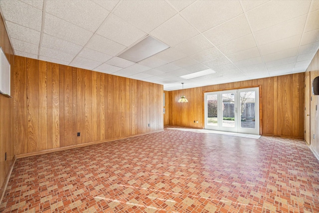 interior space with a paneled ceiling and wood walls